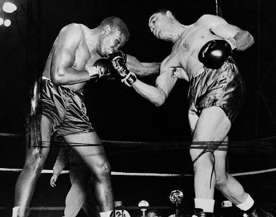 A black and white photo capturing the intense punching action as two boxers engage in a gripping fight in a ring.