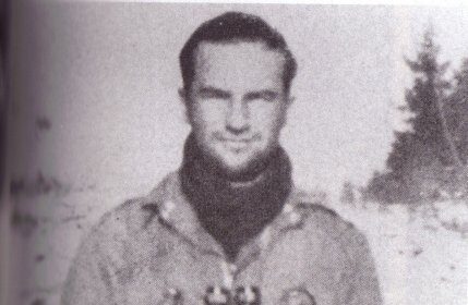 Ron Speirs, a man from Easy Company, standing in the snow with a rifle.
