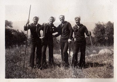 Three sailor men **posing** for a photo on a **hike**.