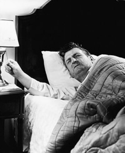 Vintage man waking up in grumpy mood and turning on the lamp.