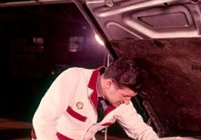 A man is learning how to change the car's air filter while working under the hood.