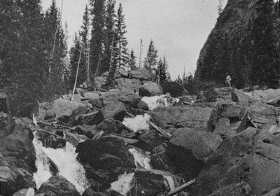 A minimalistic black and white photo showcasing the manliness of a waterfall nestled amidst mountainous landscapes.