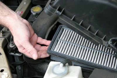 Man remove dirty air filter under car hood.