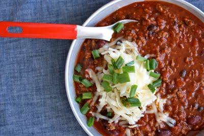 Red chili beans and meat with topping of cheese and green onion.