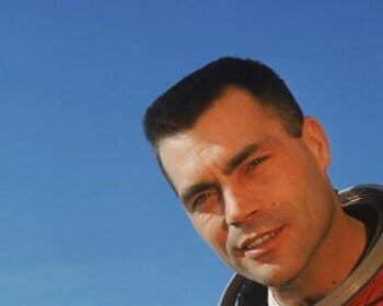 Nick Piantanida, a man with a passion for skydiving and space exploration, wearing an orange space suit, grips his helmet tightly.