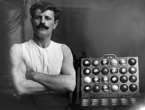 Man posing with billiards balls in sleeveless white shirt. 