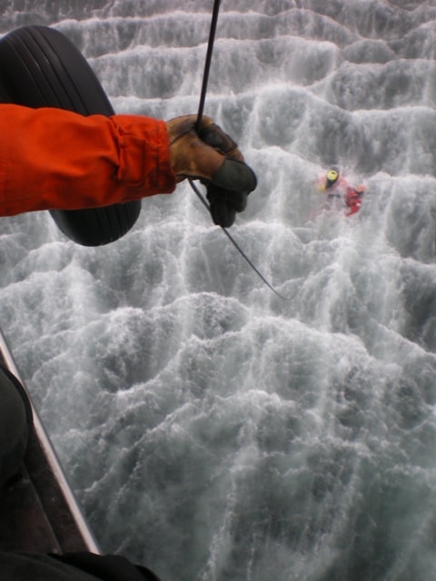 Adam Sustachek coast guard rescuing another coast guard from ocean through helicopter.