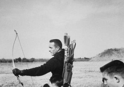 Taking aim, a man and boy engage in traditional archery with their bows and arrows.