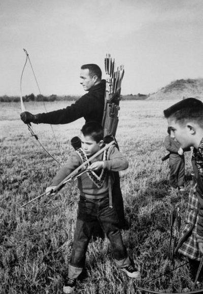 Taking aim, a man and boy engage in traditional archery with their bows and arrows.