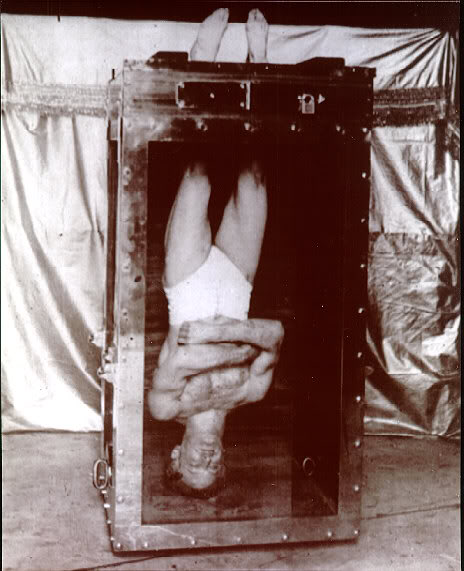 Harry Houdini locked upside down in water torture cell.