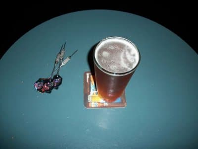 beerdarts darts on table next to pint of beer