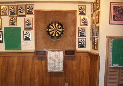 A room with a dart board and darts. The players aim for the bullseye while playing darts.