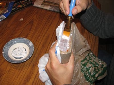 Brushing glue on the outside of the pages of book.