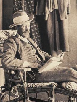 Lord Carnarvon reading a book while sitting.