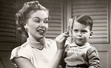 An old black and white photo capturing the tender moment of a woman brushing a child's hair.