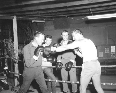 Two boxers having a bout in front of their friends in boxing ring.