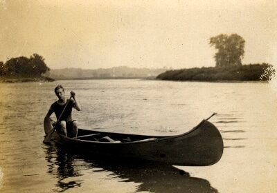 A man canoeing on a river with his paddling partner.