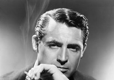 A man in a suit with Cary Grant Shine smoking a cigarette.