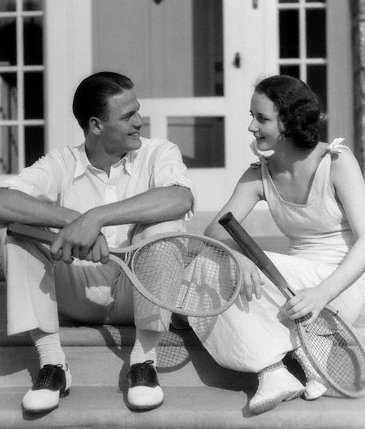Couple sitting on stairs with wooden tennis racket. 