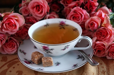 A cup of white coffee with pink fragrance rosees.