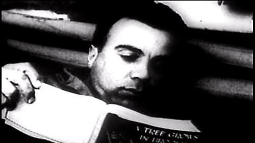 Black and white photo of a man reading a book from the Armed Services Edition Books.