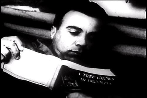 Black and white photo of a man reading a book from the Armed Services Edition Books.