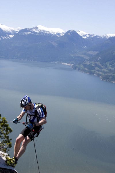 Man hiking on mountains with rappelling cliff. 