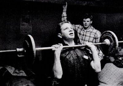 A man performing a workout with a barbell in a living room.