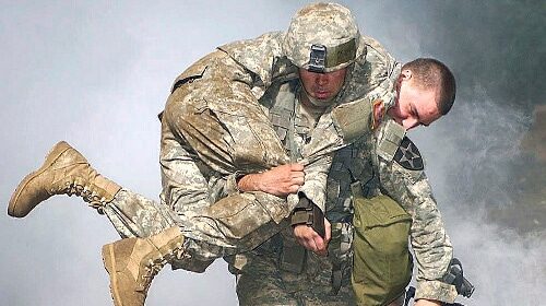 A soldier undergoes a heroic training by carrying another soldier to safety as part of the Carry a Person to Safety Workout.