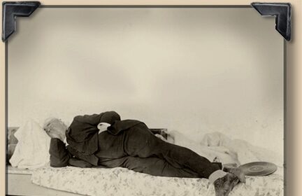 An old photograph of a man napping on a bed.