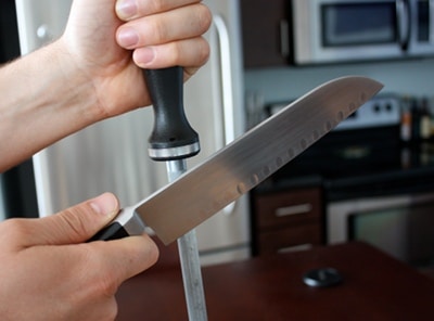 Chef sharpening the kitchen knife with steel rod.