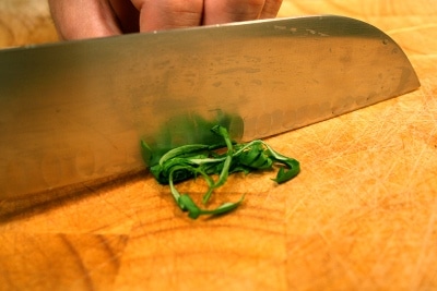 Man chopping the herbs leaves with knife.