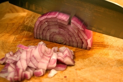 Cutting onion into small pieces with knife. 