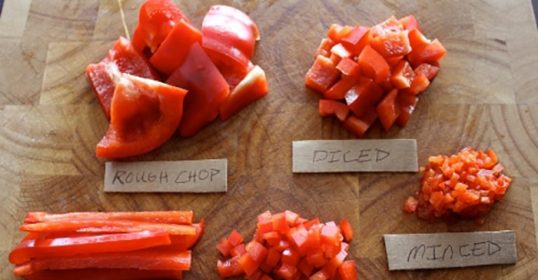 Various types of red peppers on a cutting board showcasing excellent knife skills.
