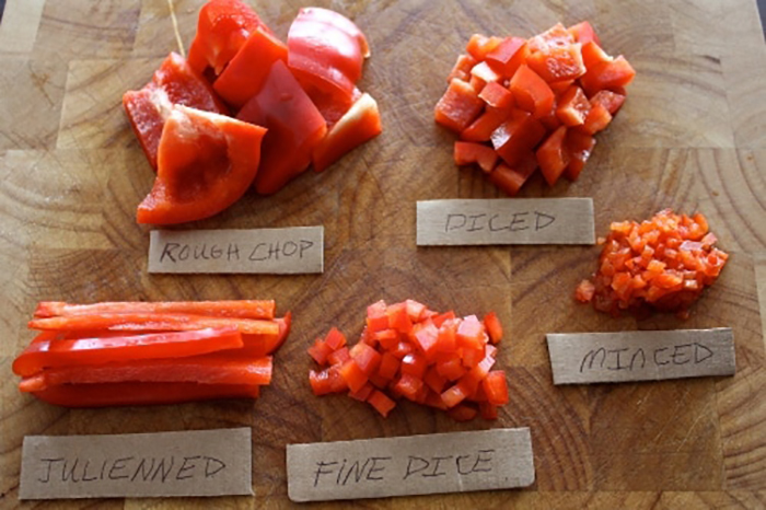 Various types of red peppers on a cutting board showcasing excellent knife skills.