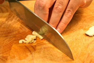Man chopping garlic with knife.