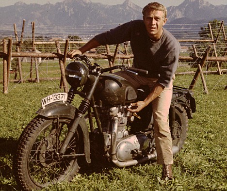 Steve Mcqueen riding on motorcycle in mountain area.