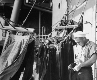 A man is washing denim clothes on the deck of a ship.
