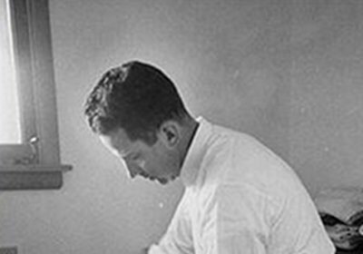 A man meticulously ironing a dress shirt properly in a room.