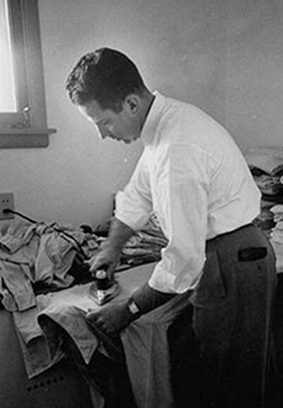 A man meticulously ironing a dress shirt properly in a room.
