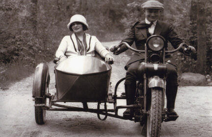 A married couple riding a motorcycle with a sidecar.