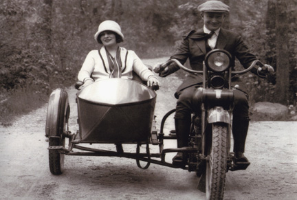 A married couple riding a motorcycle with a sidecar.