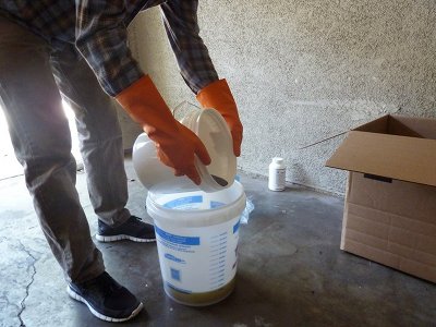 Man mixing oils and liquid in bucket for homemade soap bars. 