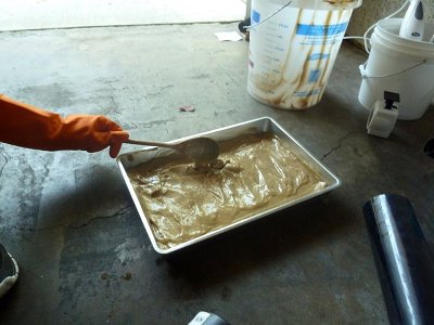 Man pouring molds into baking sheet for homemade soap bars.