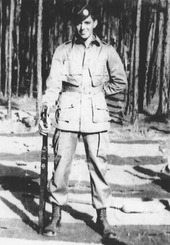 A confident man, Shifty Powers, holding a rifle in a black and white photo.