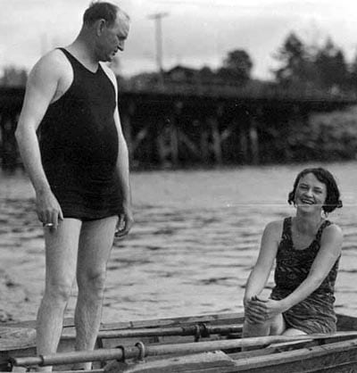 vintage man standing in row boat bathing suit