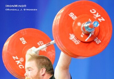 An Olympic hopeful squatting with a barbell in front of him.