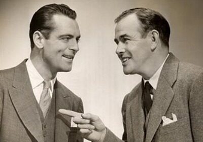 Two conversational men in suits talking to each other while avoiding narcissism.