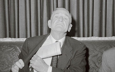 A man in a suit relaxing on a couch.