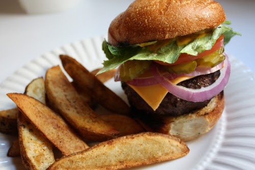 Grilled hamburger with french fries in the paper plate.